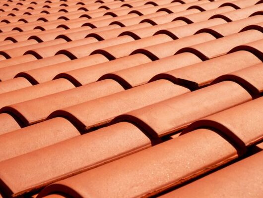 Close-up of a roof with evenly arranged reddish-brown clay tiles.