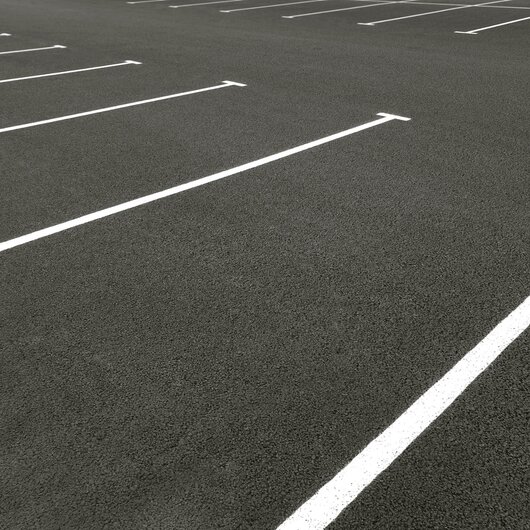 Empty asphalt parking lot with white lines marking parking spaces.